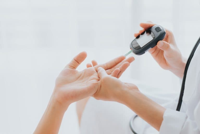 Profissional de saúde realizando teste de glicemia em paciente com aparelho medidor, representando o acompanhamento e controle do diabetes.