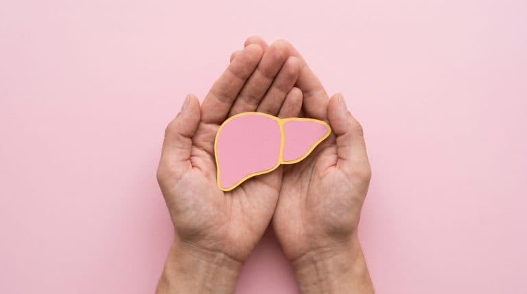 Mãos protegendo a ilustração de um fígado, representando a prevenção, os cuidados e a conscientização sobre as hepatites virais.
