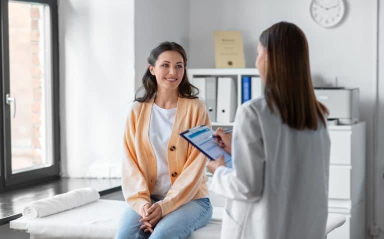 Mulher conversa com profissional de saúde durante consulta, representando o acompanhamento médico da doença falciforme.