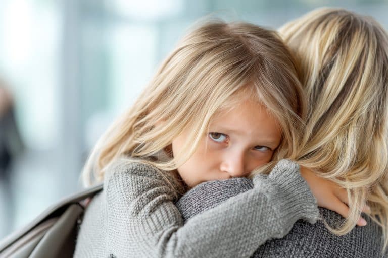 Criança abraçando a mãe com expressão triste e insegura, ilustrando o impacto emocional de uma relação familiar difícil e o debate sobre o termo narcisista na psicologia.