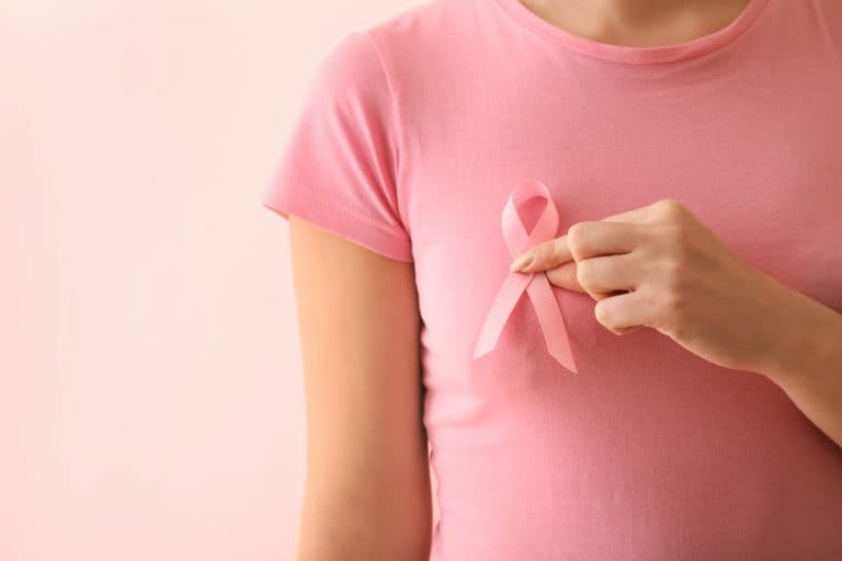 Mulher com laço rosa no peito, símbolo de conscientização e prevenção do câncer de mama.