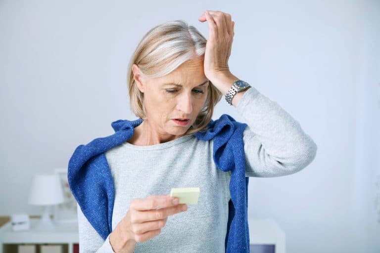 Mulher idosa demonstra preocupação ao tentar se lembrar de uma informação, representando esquecimentos e sinais de perda de memória associados ao Alzheimer.